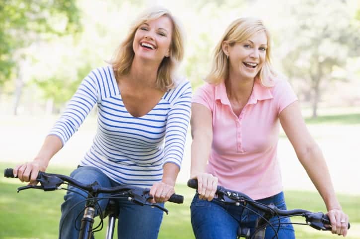 Two friends on bikes outdoors smiling